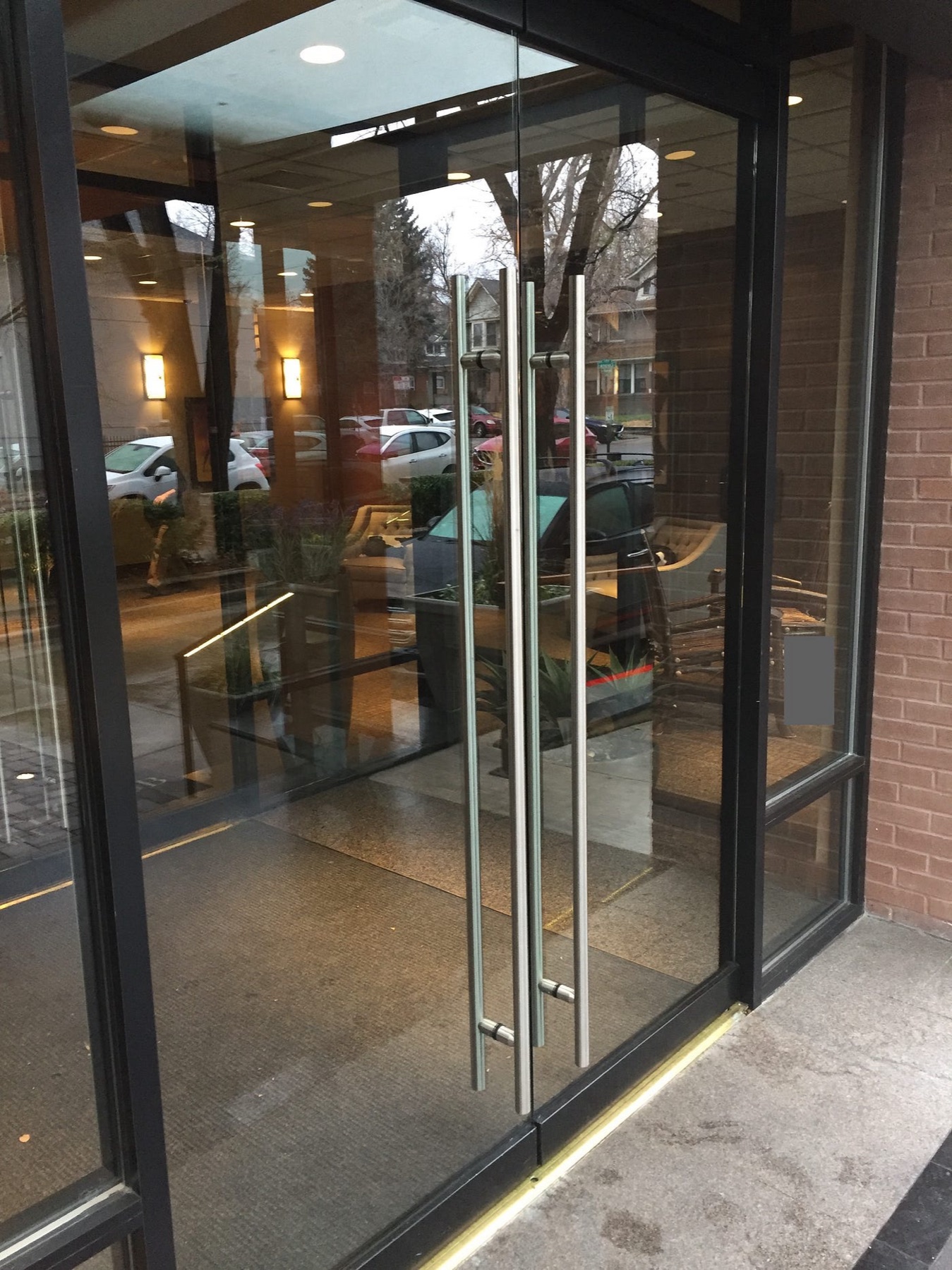 Puerta de vidrio con manijas verticales idénticas en las dos hojas: nada dice de qué lado se empuja